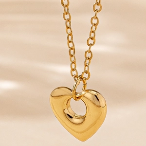 Collier à pendentif cœur évidé doré poli sur un fond de tissu en soie champagne doux