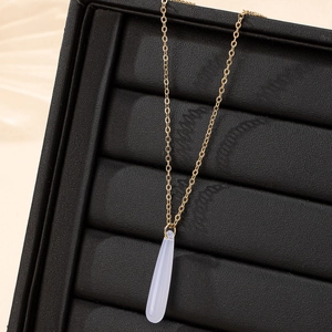 Elegant gold chain necklace with a light blue teardrop pendant on black jewelry display