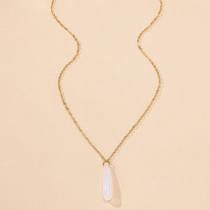 Detailed close-up of a minimalist gold chain with a soft pink teardrop stone pendant