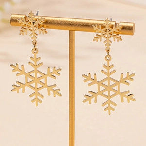 Elegant gold snowflake drop earrings displayed on a premium jewelry stand for winter