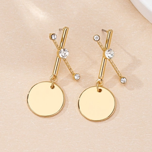 Détail de boucles d'oreilles dorées avec strass géométriques et disques en métal poli