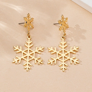 Detail of golden snowflake drop earrings with hollow hexagonal pattern on sand background