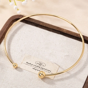 Minimalist gold ball open choker necklace with polished finish on elegant linen background