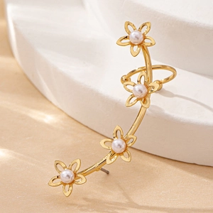 Élégante boucle d'oreille fleur dorée avec perles blanches sur surface en pierre