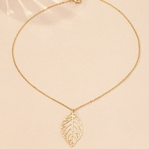 Détail macro du pendentif feuille dorée montrant les nervures délicates et le savoir-faire