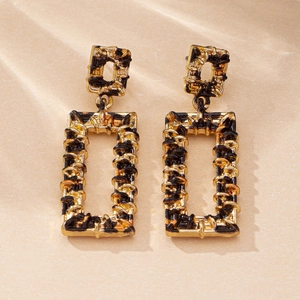 Close-up of vintage gold rectangular earrings with black textured woven inlay detail