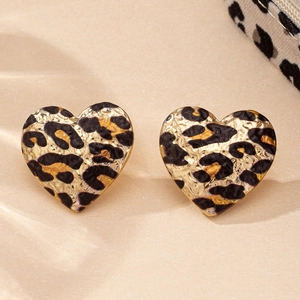 Macro shot of heart-shaped leopard print earrings with gold hammered metal base texture
