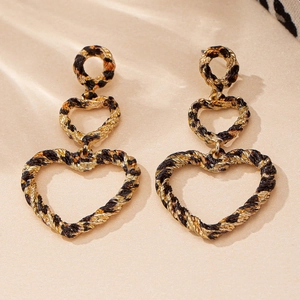 Détail des boucles d'oreilles cœur léopard avec texture en métal doré torsadé chic