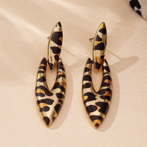 Detailed view of geometric leopard print drop earrings with gold finish on stone surface