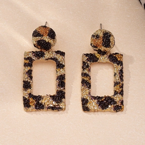 Detail of square hollow earrings with leopard print pattern and gold hammered texture
