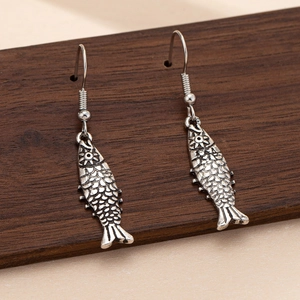 Antique silver fish dangle earrings with detailed scales on a wooden display board