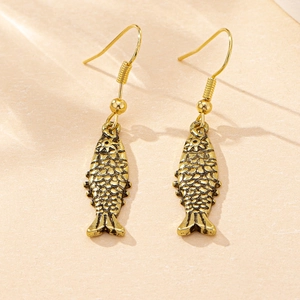 Detailed close-up of fish-shaped earrings with textured scales in vintage gold finish