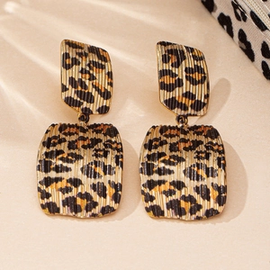 Detail of geometric leopard print earrings featuring textured metal and bold patterns
