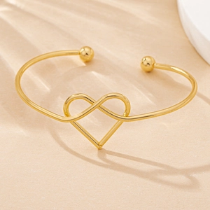 Macro detail of gold-tone infinity and heart bangle with elegant ball finials