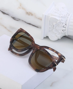 Detailed macro view of tortoiseshell square sunglasses with gold metal hinge accents