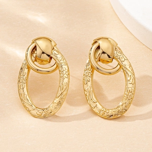 Macro detail of gold vintage oval earrings with ornate floral textures and bohemian style