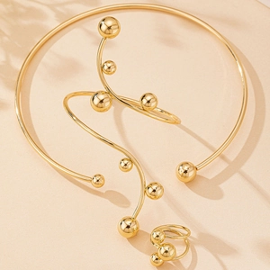 Détail d'un ensemble de bijoux à perles dorées avec choker, bracelet et bague minimaliste