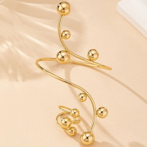 Détail d'un bracelet spirale doré et d'une bague à billes sur un décor minimaliste