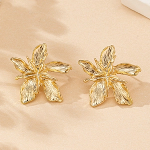 Vue détaillée de boucles d'oreilles fleur dorées avec texture de métal brossé
