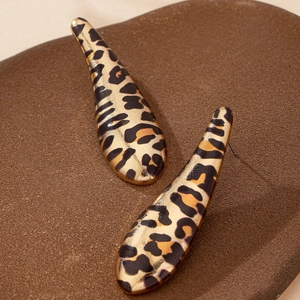 Fashionable leopard print teardrop earrings with gold base on brown textured display