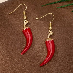 Macro detail of red chili earrings with gold hooks on textured background