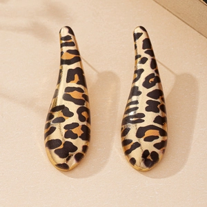 Detail shot of teardrop leopard print earrings with gold-tone base on a sandy texture surface