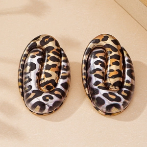 Macro detail of oval leopard print earrings featuring a polished gold and brown finish