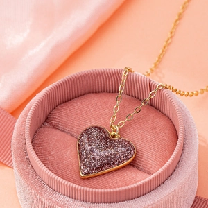 Dettaglio del ciondolo a cuore glitterato rosa su catena dorata in scatola velluto