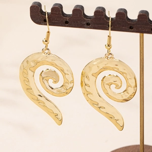 Elegant gold spiral drop earrings with hammered texture on a wooden jewelry display stand