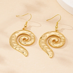 Macro detail of elegant golden spiral drop earrings with hammered metal texture finish