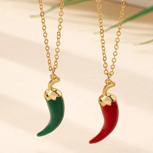 Vue détaillée des pendentifs piment en émail rouge et vert sur chaînes dorées