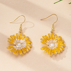 Détail de boucles d'oreilles marguerite avec pétales blancs et crochets dorés sur fond nature
