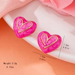 Boucles d'oreilles cœur rose avec bord doré et texture marbrée sur plateau blanc