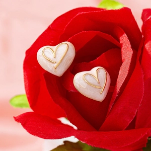 Boucles d'oreilles cœur en émail avec texture marbre nichées dans une rose rouge