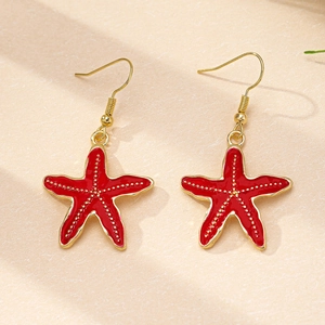 Vue détaillée de boucles d'oreilles étoiles de mer en émail rouge avec bords dorés élégants
