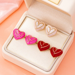 Trois paires de boucles d'oreilles en forme de cœur rose et rouge dans un écrin à bijoux