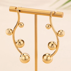 Elegant gold curved branch stud earrings with polished metallic beads on a display stand