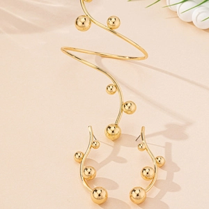 Detail of gold spiral arm cuff and matching stud earrings with metal bead accents