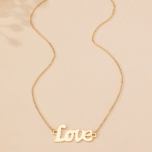 Détail d'un collier avec pendentif Love doré élégant sur un fond crème texturé