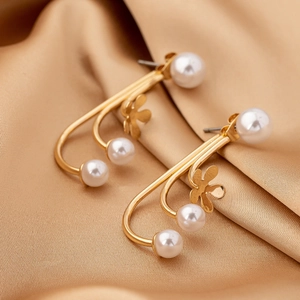 Elegant gold flower pearl earrings with curved white pearls on champagne satin background