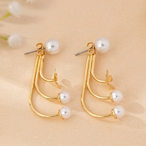 Detail of gold-plated curved metal earrings with four white pearls and tiny flower accents