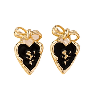Vintage heart earrings with gold bow, black enamel and rose relief on white background