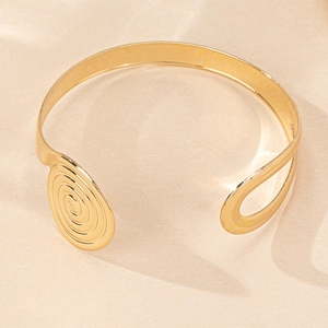 Detailed macro shot of elegant golden spiral geometric open cuff bracelet for women