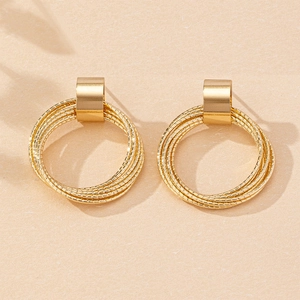 Detail of layered gold hoop earrings with textured rings and polished rectangular clasps