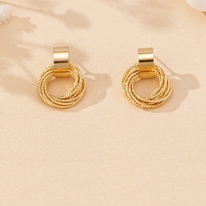 Macro view of gold layered twisted circular drop earrings with textured surface