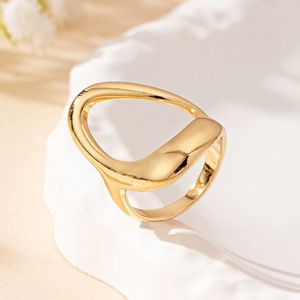 Elegant gold minimalist ring with irregular hollow design on white textured tray