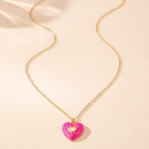 Detalle de colgante de corazón en esmalte rosa jaspeado con pequeño corazón y cadena dorada