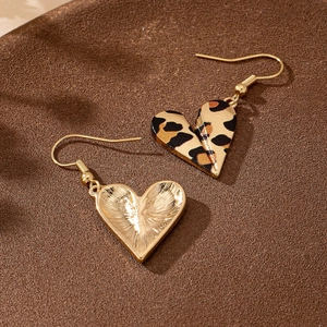 Retro leopard print heart earrings with golden metal back on dark textured background