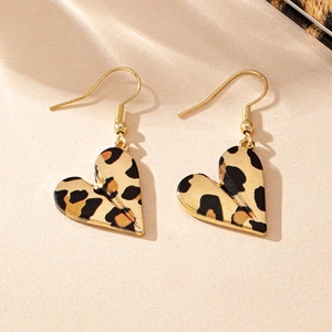 Detail shot of heart-shaped leopard print earrings with gold hooks on beige texture