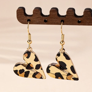 Fashionable leopard print heart dangle earrings with gold hooks on a wooden stand